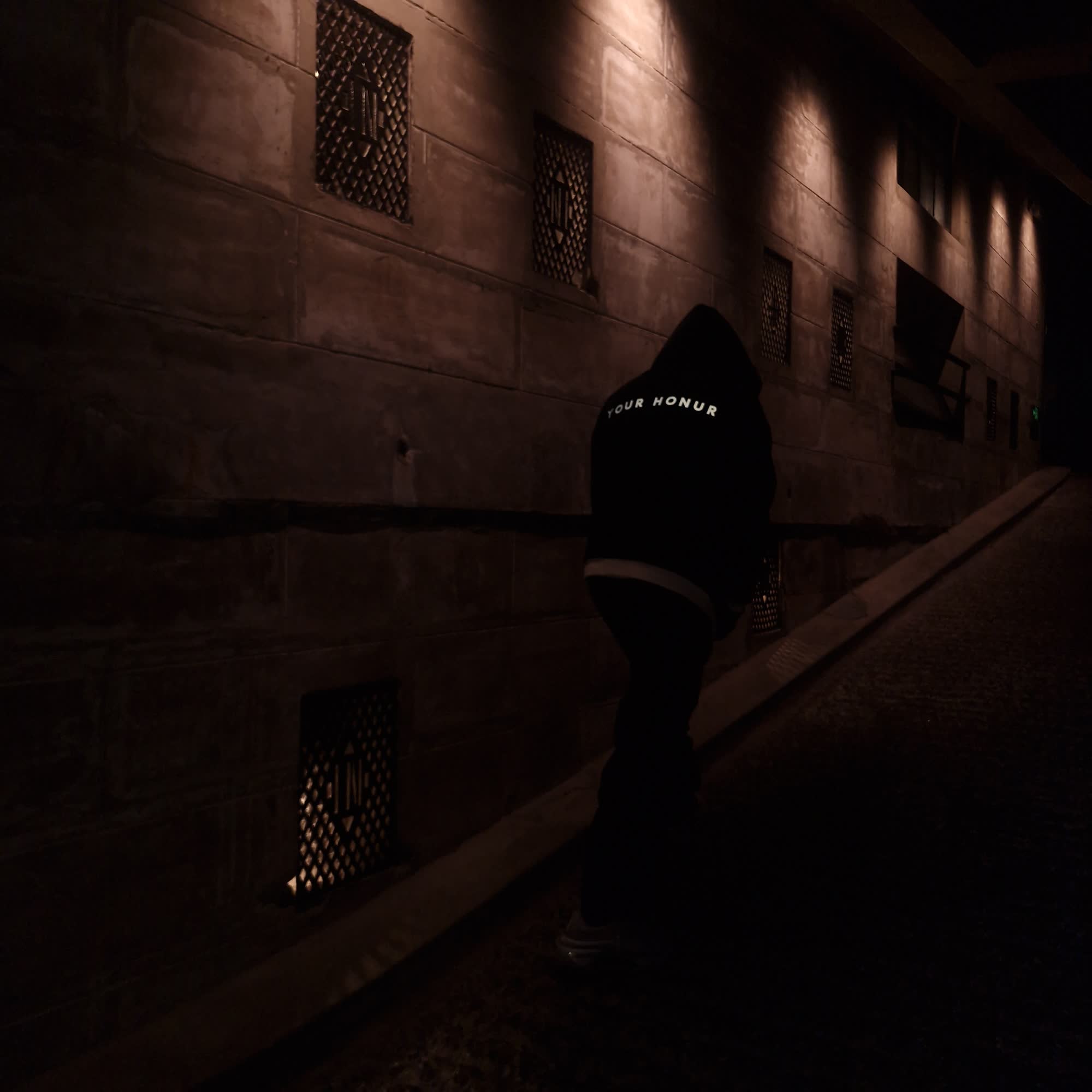 YOUR HONUR reversible heavyweight hoodie — black side, worn in a stone alley