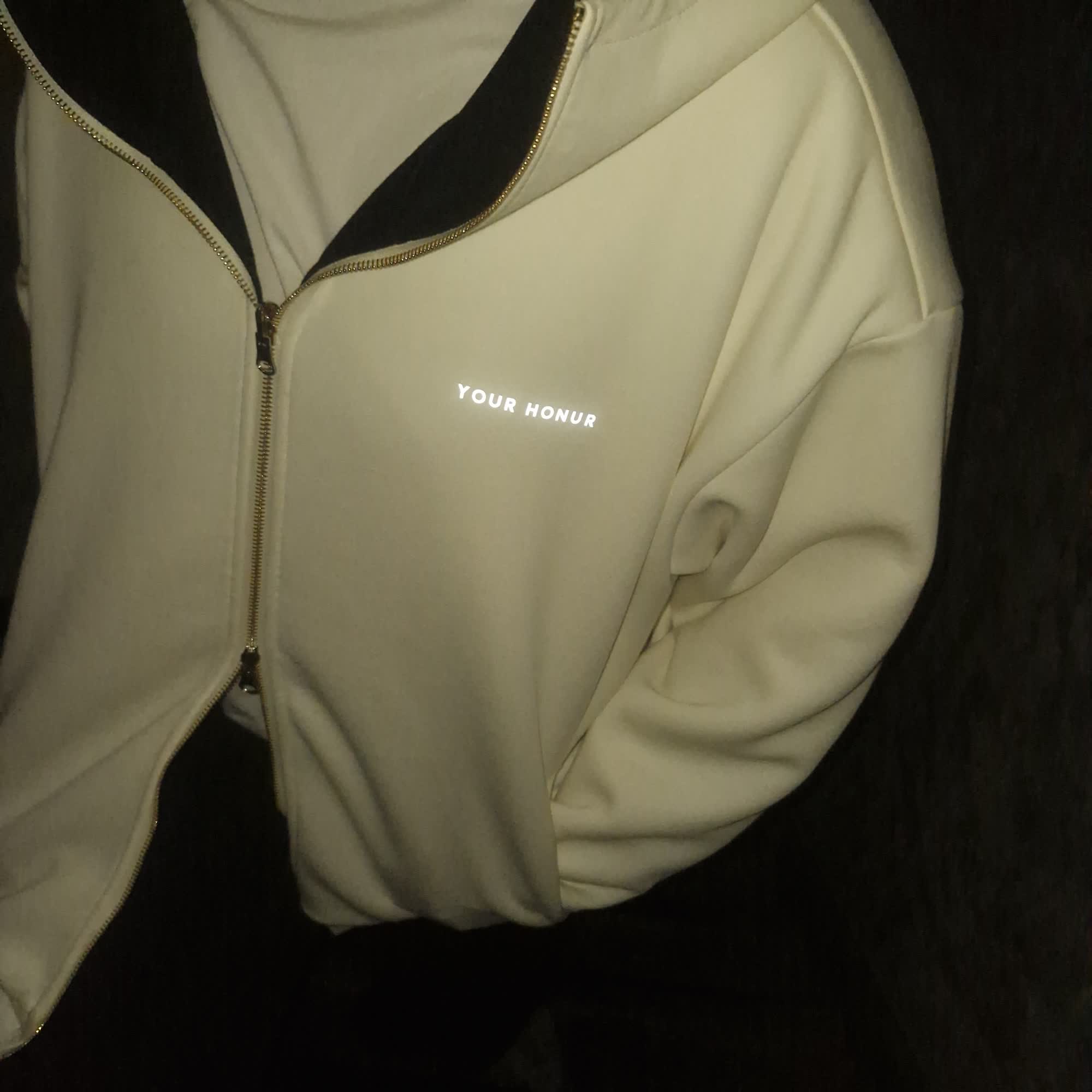 Detail of the cream side — chest mark and gold zipper